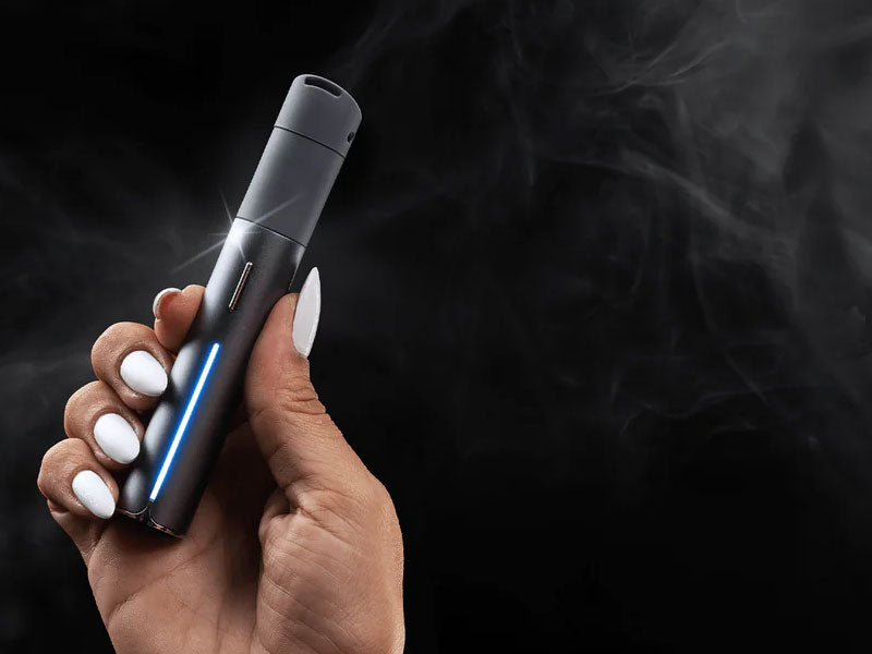 Woman holding Puffco Pivot with black background and smoke